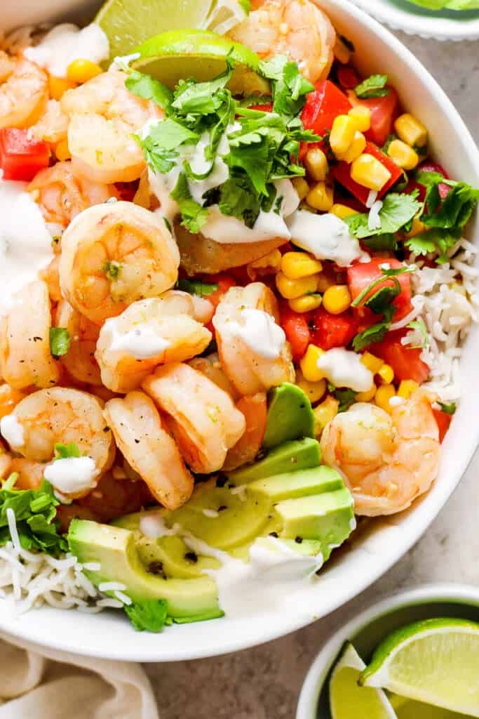 A white bowl with shrimp, rice and avocado.