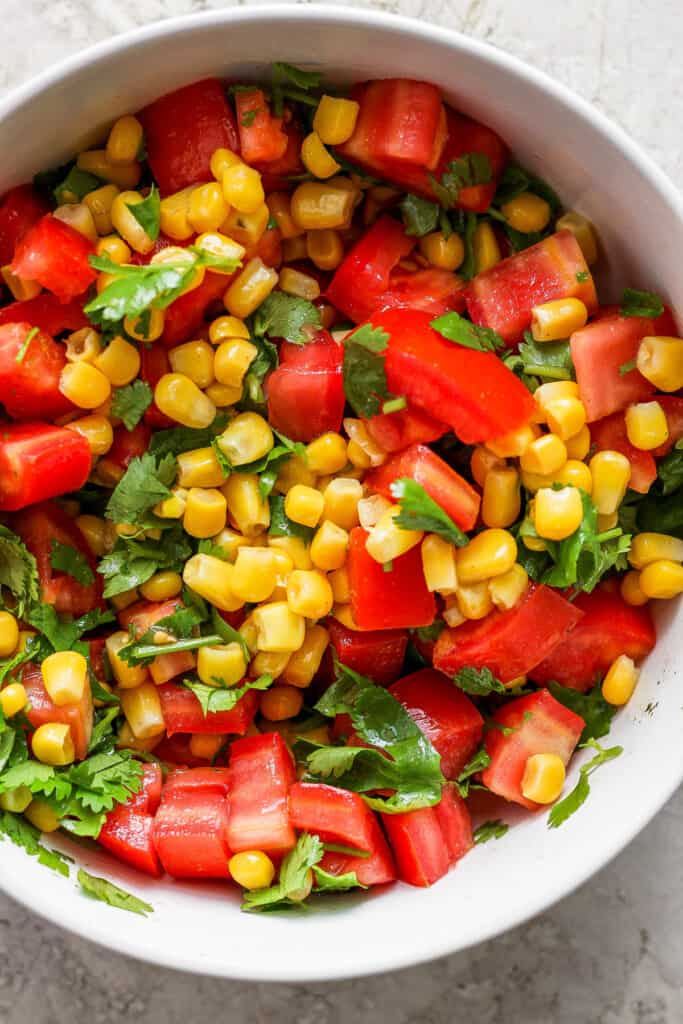 Corn and tomato salad in a white bowl.