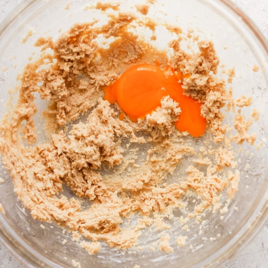 A bowl filled with a mixture of flour and an egg.