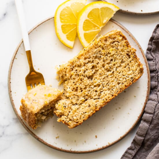 Lemon poppy seed bread on a plate next to lemon slices.