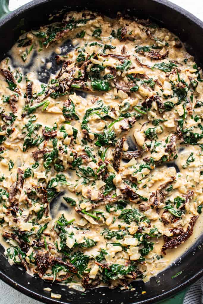 A skillet filled with spinach and mushrooms.