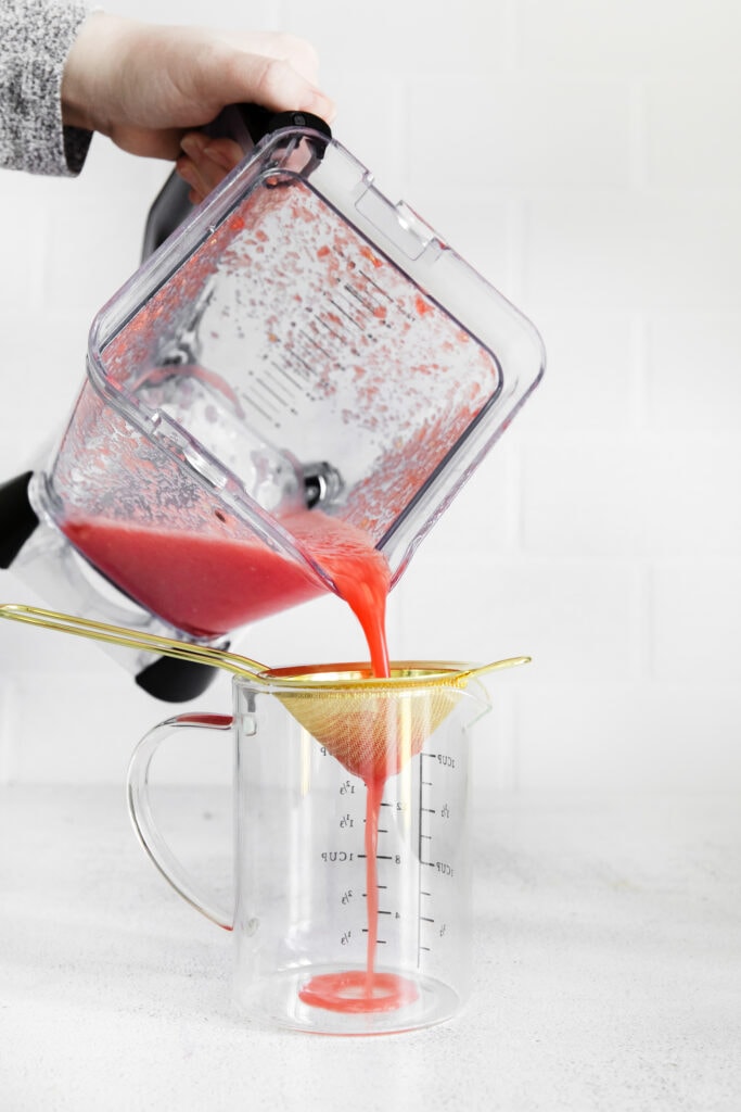 Pouring blended watermelon through a sieve. 