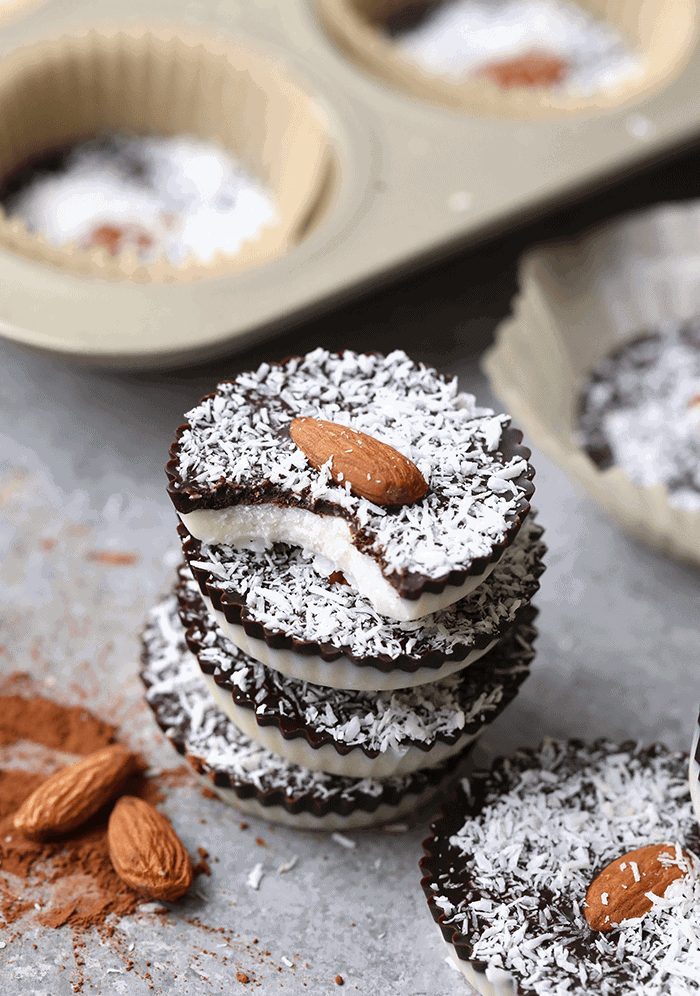 a stack of coconut butter cups with chocolate and almond filling in a muffin tin.