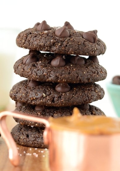 A stack of double chocolate peanut butter cookies on a wooden cutting board.