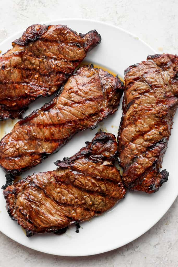 4 large grilled steaks on a plate.